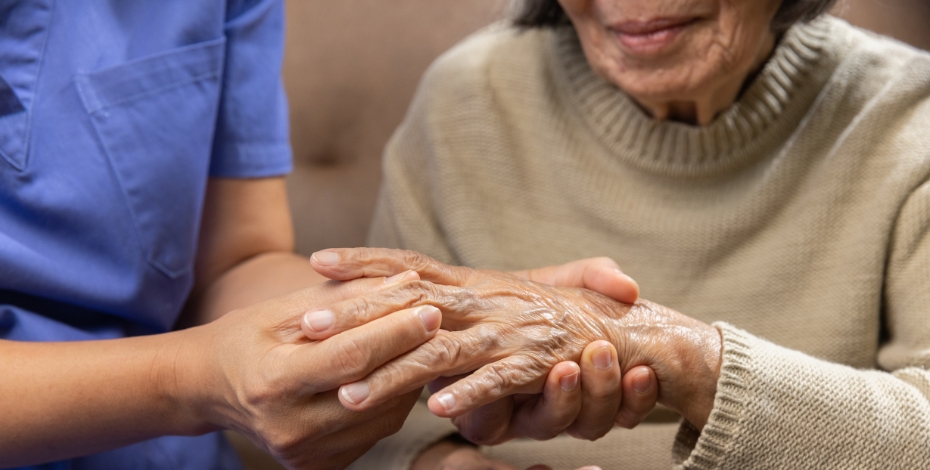 an elderly woman's hand being held by a health professional