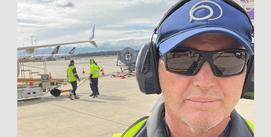 Troy Eady is pictured standing on the tarmac at Brisbane Airport where he works as an occupational health physiotherapist.