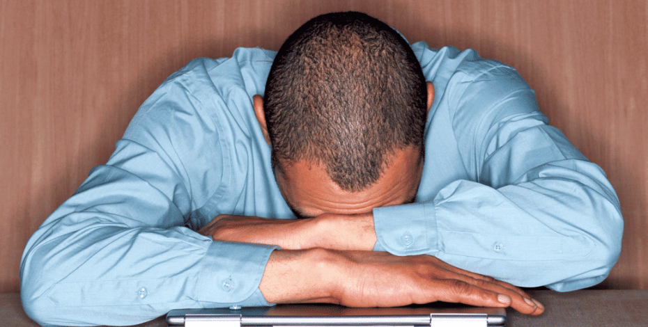 Man sitting with his head down, resting on his hands