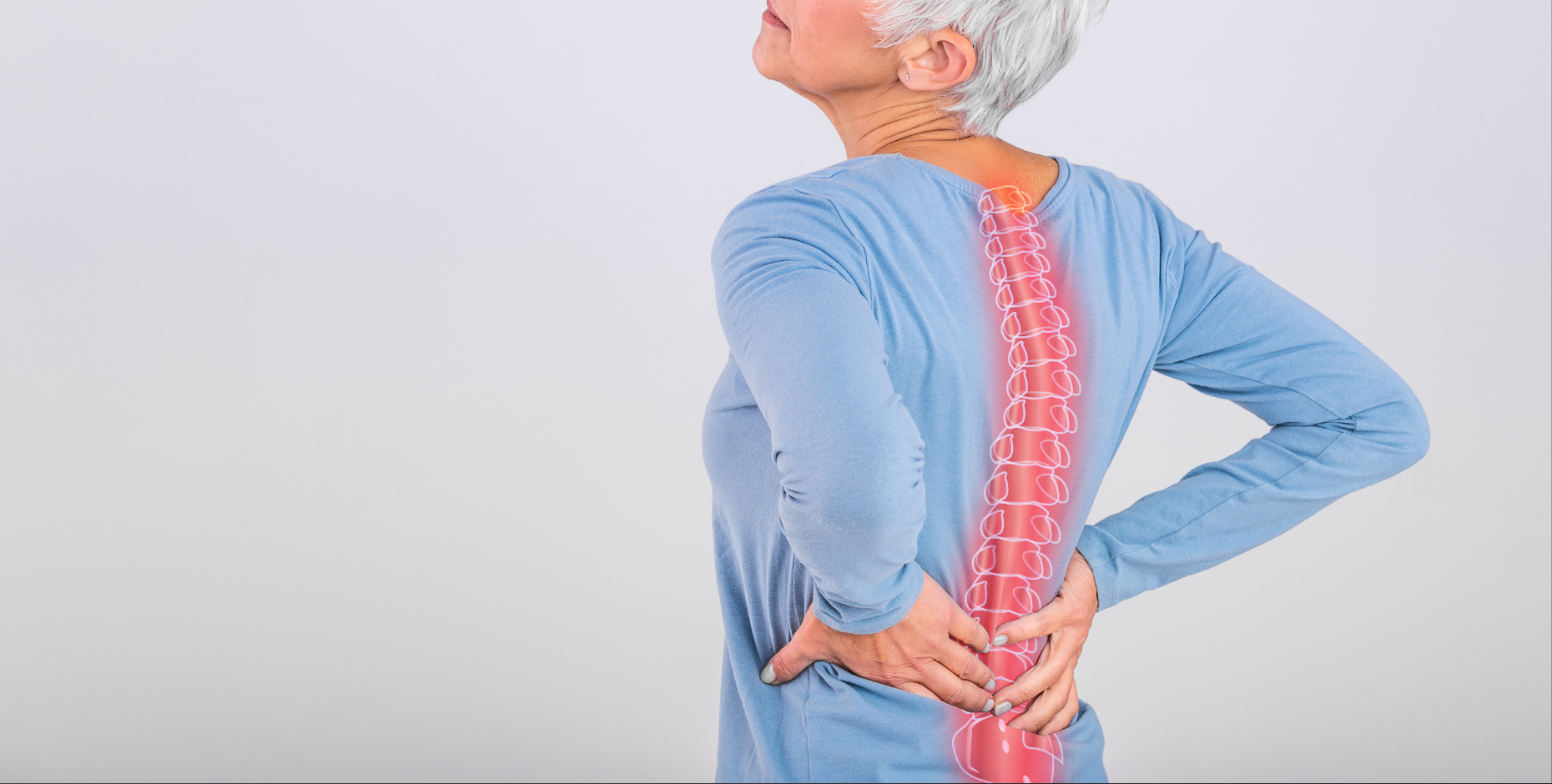 Older woman in a blue long sleeve top clutching at her lower back