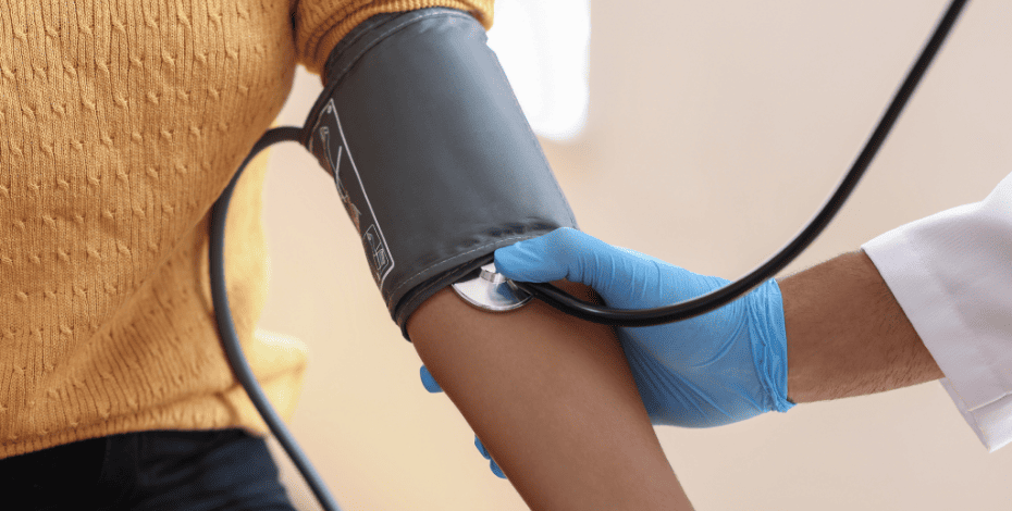 A clinician is measuring a patient's blood pressure, using a blood pressure cuff and a stethoscope. 