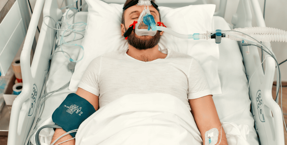 Man lying on a hospital bed using a ventilator