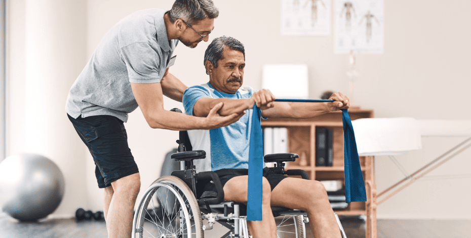 Man in a wheelchair being helped by a physiotherapy to do his exercises.