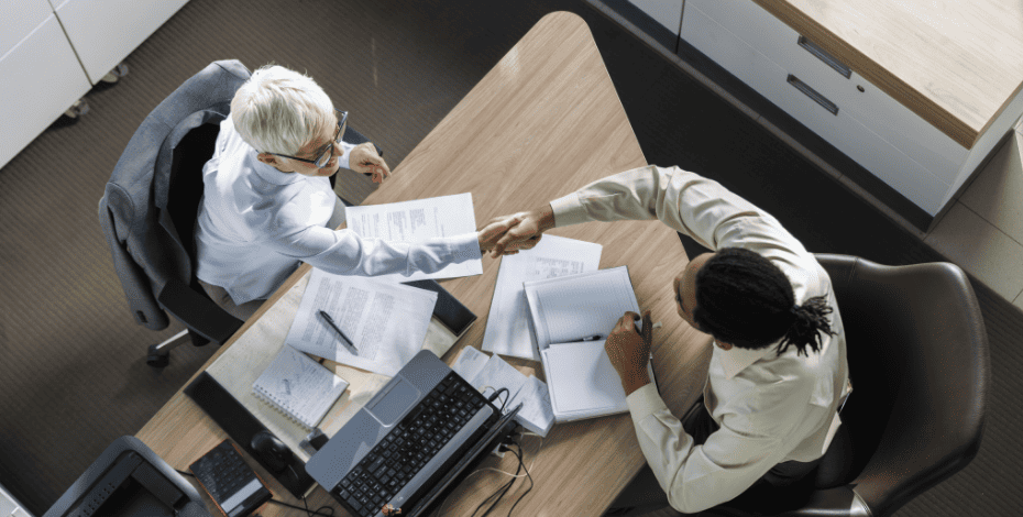 Hands shaking across a desk as if welcoming a new employee after the interview process.