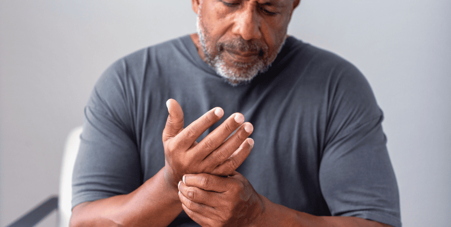 A man rubs his hand as if he is in pain.