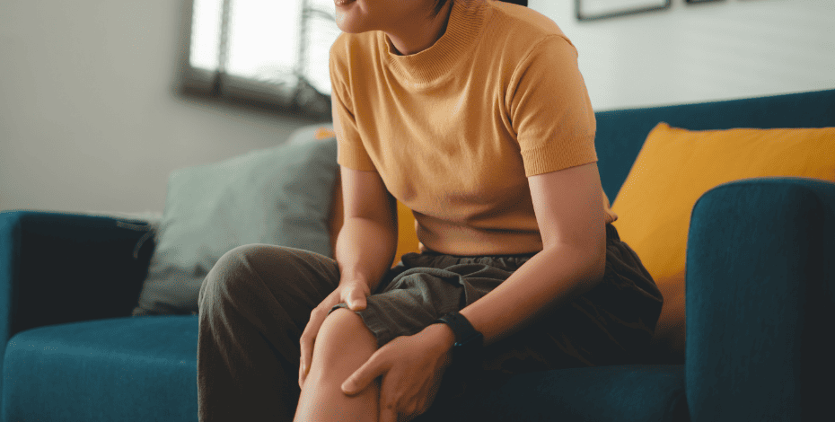 Woman sitting on the couch, clutching her knee
