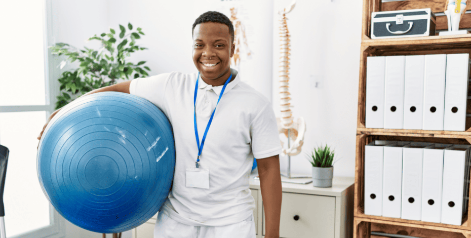 A physiotherapist smiling and holding an exercise ball