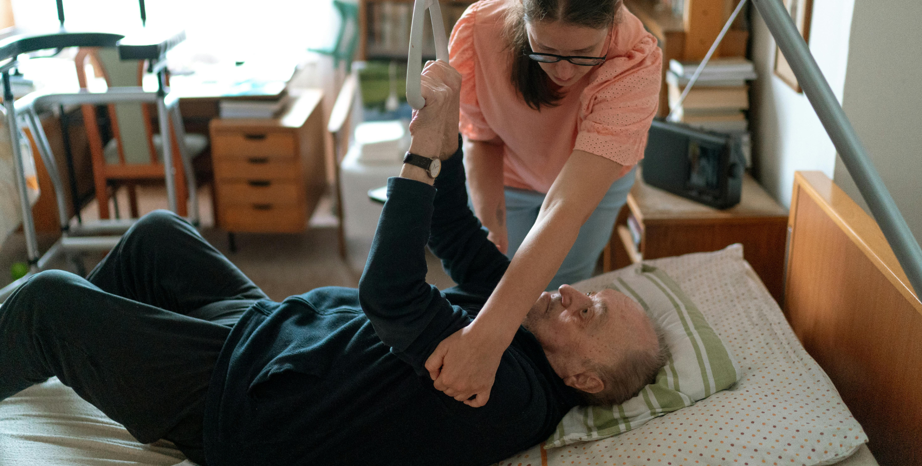 A physiotherapist assisting an older person to get out of bed.