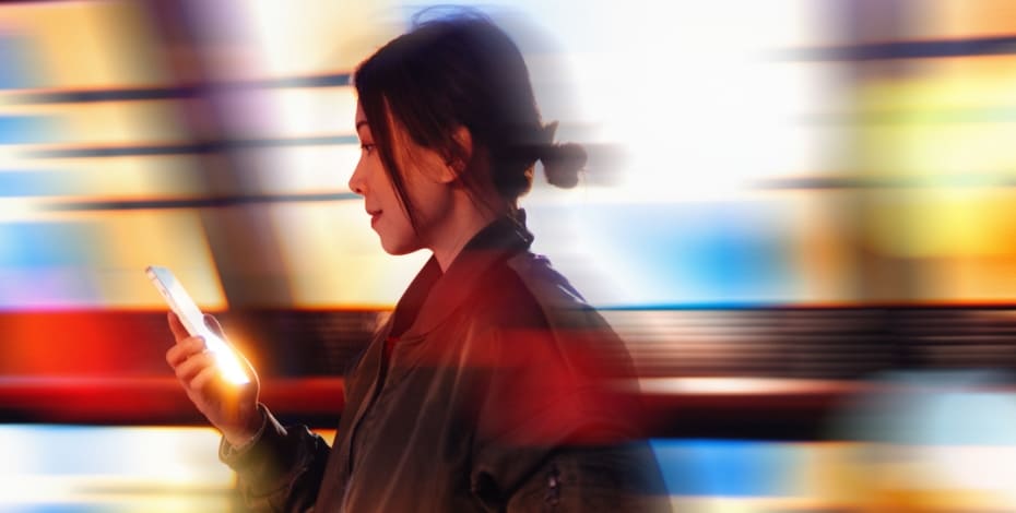 Stylised image of woman looking at her phone in front of a blurry background.