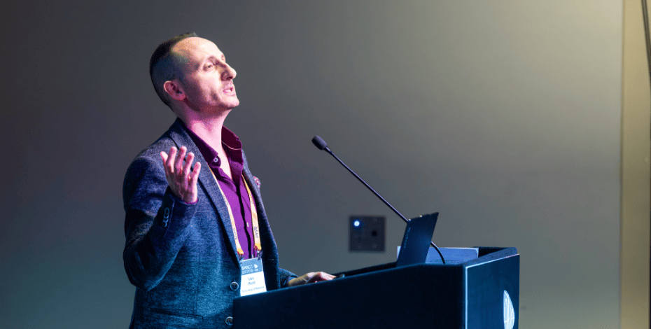 the image is of Associate Professor Mark Meroli speaking at APASC25