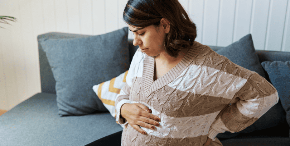 A pregnant woman holding her back and belly