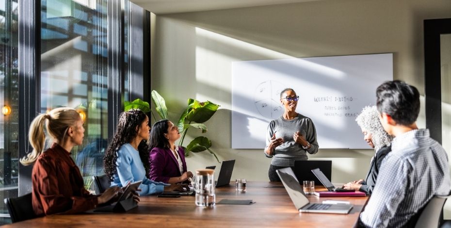 A person speaking to employees in a boardroom