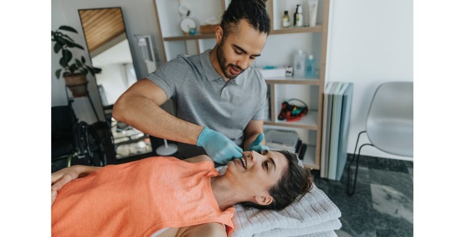 The image is of a physiotherapist working with a patient on her jaw. 