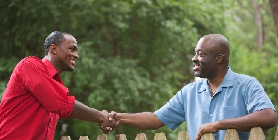 Two men shaking hands over a fence.