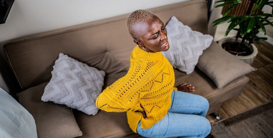 A woman with lower back pain sitting on a couch