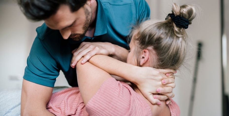 Male physiotherapist closely treating a female patient 