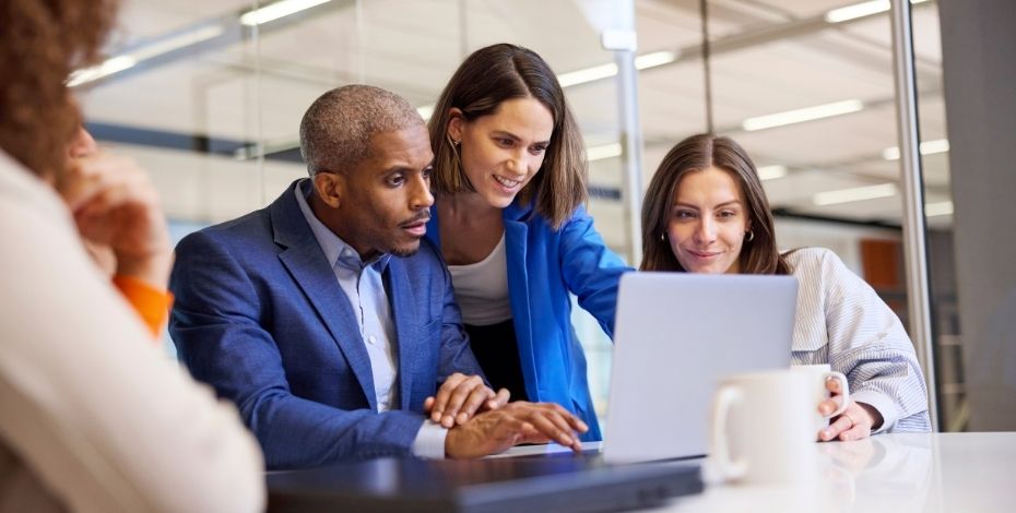 Three colleagues look at a computer together 