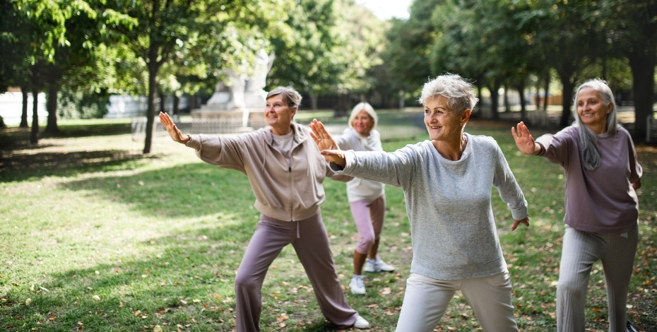The photo shows a group of older people doing tai chi exercises in a park