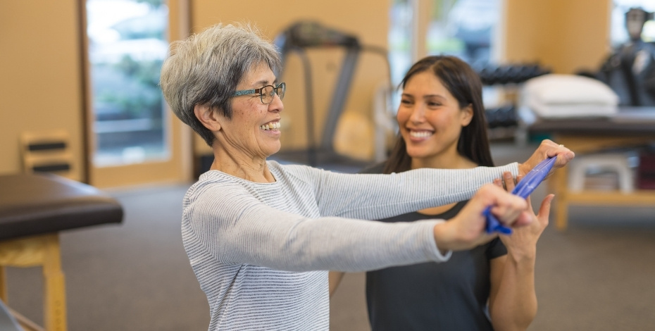 A physiotherapist helps an elderly woman exercise to improve her balance.