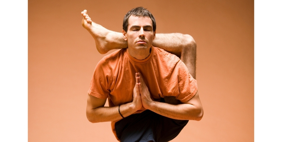 A man is bending his leg behind his head to display hyperflexion.