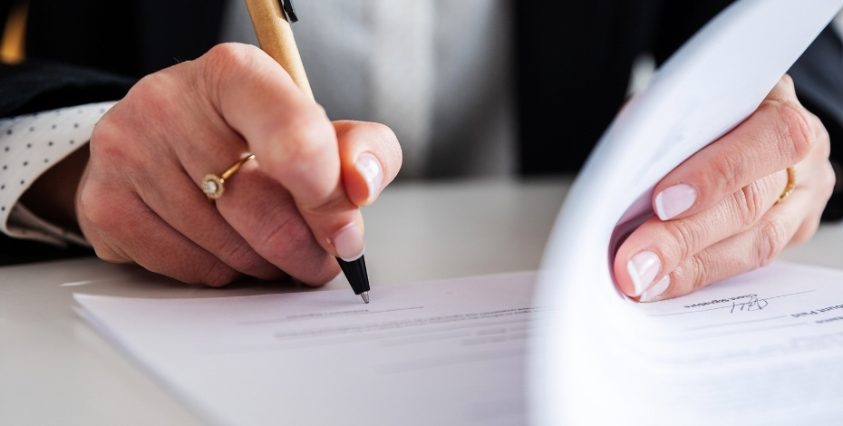 An image of a business woman's hands signing an employment contract. 