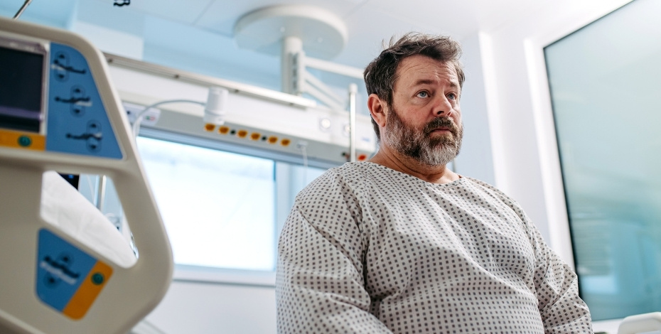 A patient sitting on the edge of a hospital bed.
