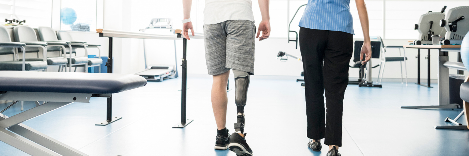 Two people walking away, one on the left uses a prosthetic leg