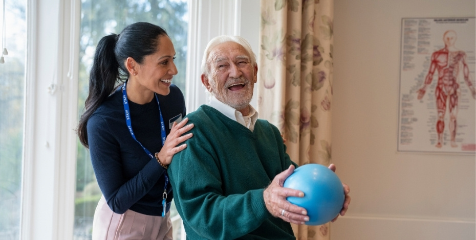 A physiotherapist smiling at an elderly patient 