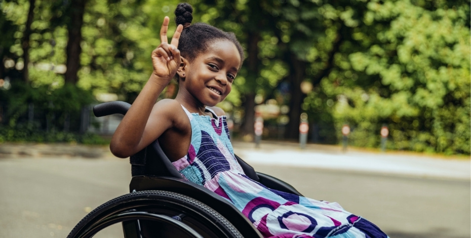 A girl in a wheel chair throwing up a peace sign 