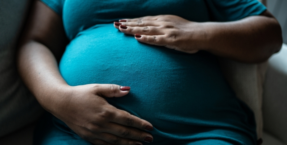 A woman with her hands on her pregnant stomach 