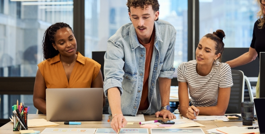 A group of people gather around a desk to brainstorm. 