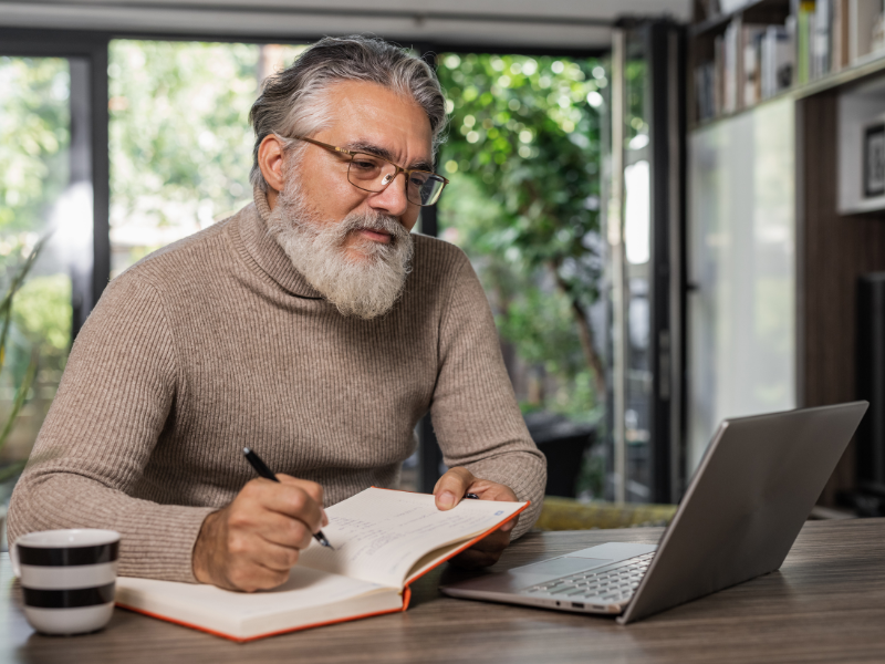Man with notebook looking at laptop