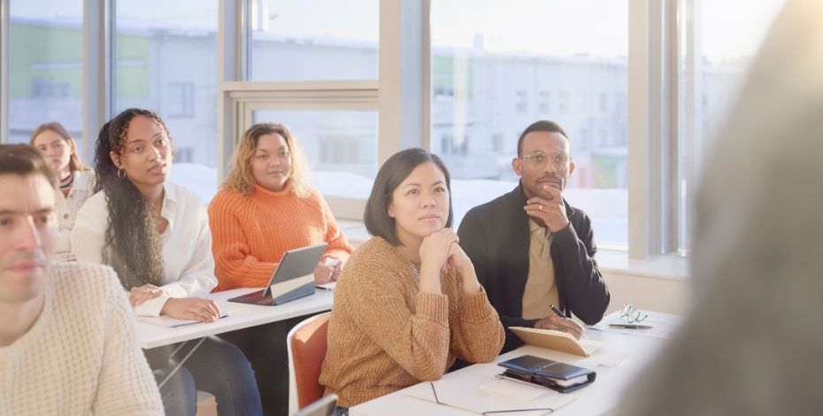 Adult students sit listening to their teacher