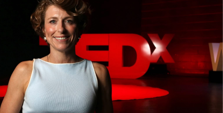 Physiotherapist Kylie Moffitt stands in front of a TEDx sign. 