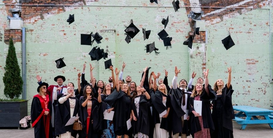 Graduates of the UTAS Master of Physiotherapy program throw their graduation caps in the air.