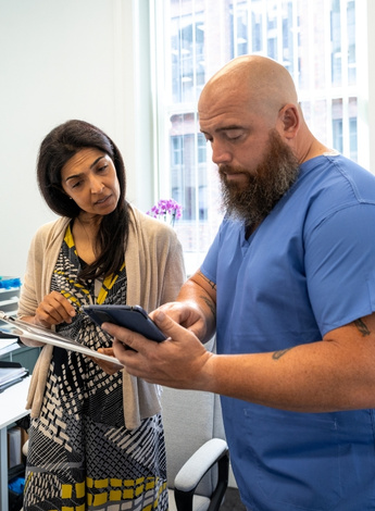 A male physiotherapist shows his female colleague something on a tablet computer