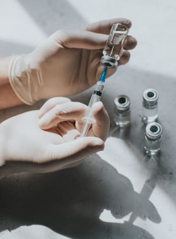 The image is of a hypodermic syringe being filled with medicine.