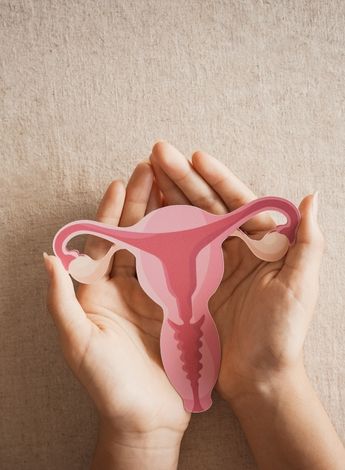 A woman holds a paper cut out of a uterus