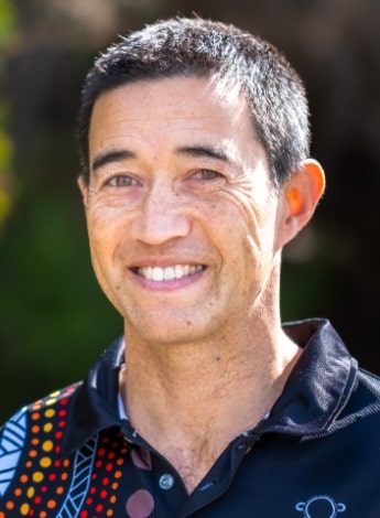 The image is of a dark haired Asian man wearing a shirt with an Aboriginal design on it. 