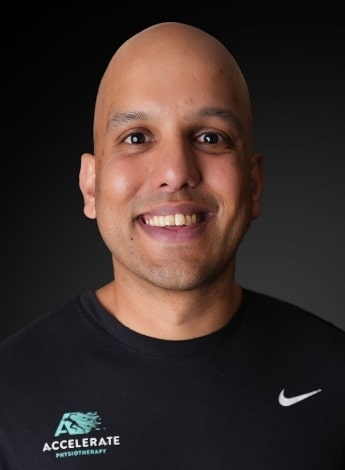 The image is of a balding man with olive skin, against a dark background. 