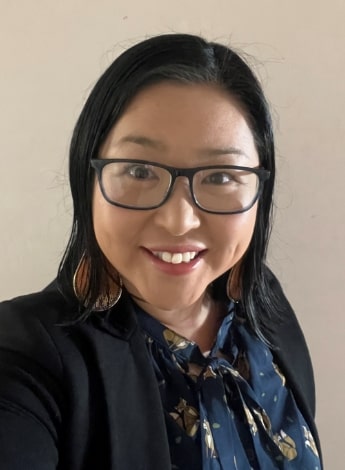 An Asian woman wearing glasses and a dark blue top