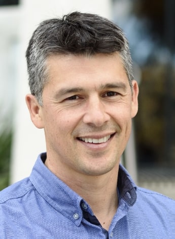 A grey-haired man is wearing a blue shirt