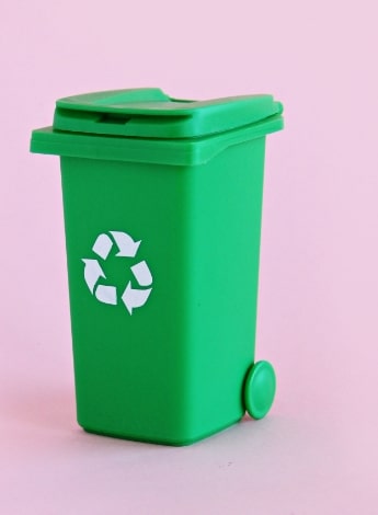"green recycle bin on a pink background"