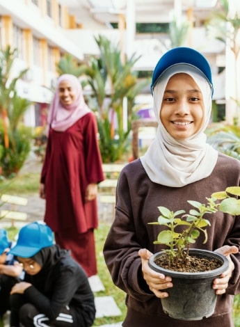 "person smiling holding a pot plant"