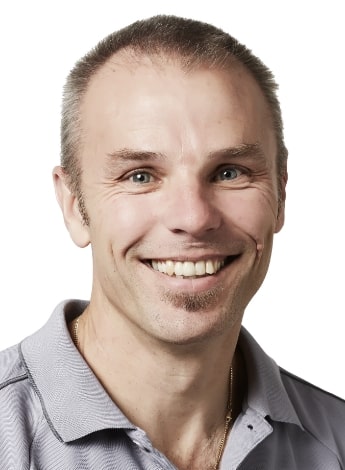 The image is of a man with short brown hair, wearing a grey shirt