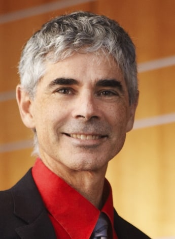 A man with grey hair is wearing a red collared shirt