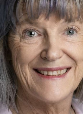 The image is of an older woman's face. She has grey hair and blue eyes and is smiling at the camera.