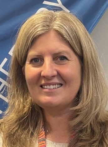 A woman with long wavy blonde hair is looking at the camera