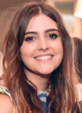 "A woman with shoulder length brown hair is smiling at the camera. "