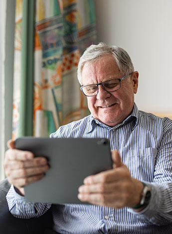 ""older man smiling at ipad